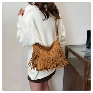 Borsa tote in camoscio marrone con lunghe frange indossata su un maglione di maglia bianco