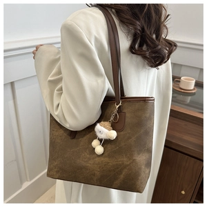 Retro brown tote bag with plush charm shown on shoulder for a minimalist college style
