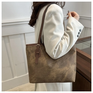 Detail of a large brown tote bag with vintage texture and adjustable metal buckle strap