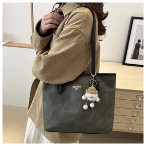Close-up of vintage suede tote bag with leather strap and cute sheep plush charm