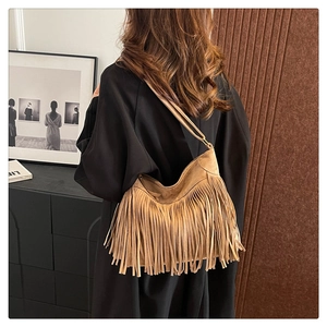 Detailed view of bohemian brown suede hobo bag with fringe tassels on model