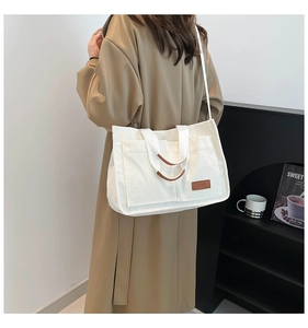 Detail of corduroy tote bag with dual front pockets and brown leather brand tag