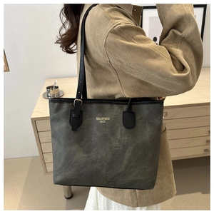 Close-up of charcoal gray tote bag with adjustable black straps and gold-tone hardware