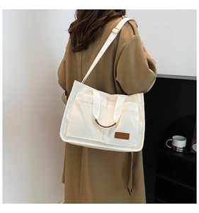 Detailed close-up of white corduroy tote bag with fashion label and adjustable strap
