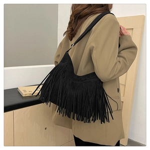 Detail of bohemian black suede crossbody bag featuring long flowing fringe tassels