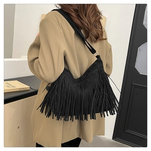 Dettaglio della texture in pelle scamosciata nera e lunghe nappe su questa borsa a tracolla