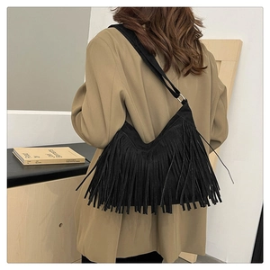 Detailed view of black suede shoulder bag featuring long fringe and bohemian tassel design