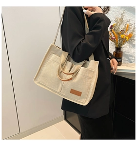 Detail of corduroy tote bag with dual front pockets and contrast leather handle stitching