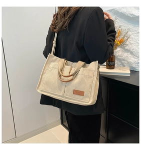 Detail of beige corduroy tote bag showing ribbed texture and brown fashion leather patch