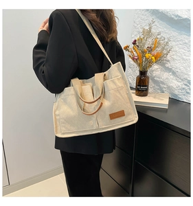 Detailed texture of off-white corduroy tote bag with fashion label and shoulder strap