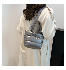 Silver-grey quilted down bucket bag styled as a crossbody on a person in a minimalist setting