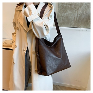 Macro detail of dark brown pebble grain leather tote showing soft texture and wide strap