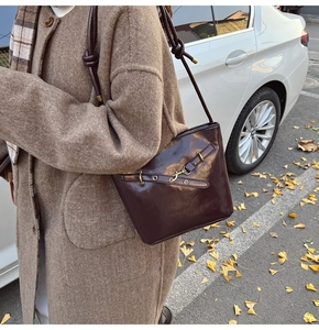 Brown leather bucket bag with vintage metal buckle shown on model in autumn street scene
