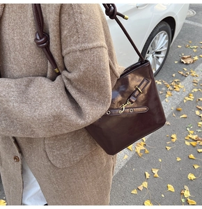 Detail of vintage brown leather bucket bag with brass hardware and knotted strap details
