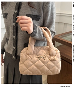 Detail of light brown quilted handbag with elegant gold bow metal accessory and texture