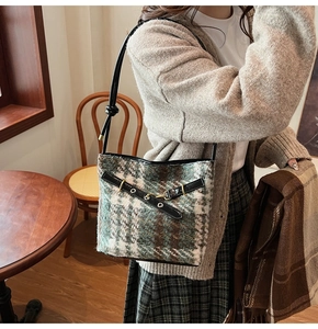 Detailed view of checkered tweed bucket bag with leather strap on a female model