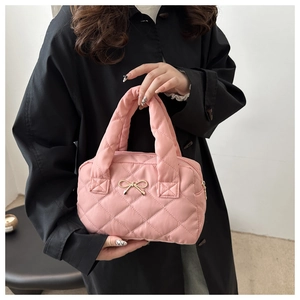 Detail of pink quilted nylon handbag with golden bow hardware and elegant top handles