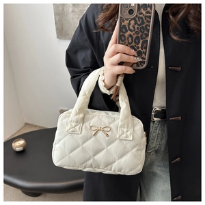 Dettaglio della borsa a cuscino trapuntata bianca con fiocco d'oro sulla modella