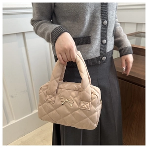 Dettaglio della borsa trapuntata beige con fiocco dorato e trama a rombi