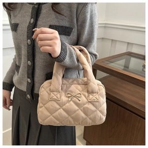 Dettaglio borsa trapuntata marrone chiaro con fiocco in metallo dorato e texture