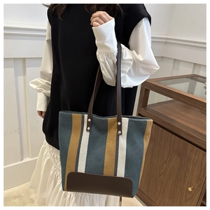 Close-up of stylish vertical striped canvas tote bag with brown faux leather straps