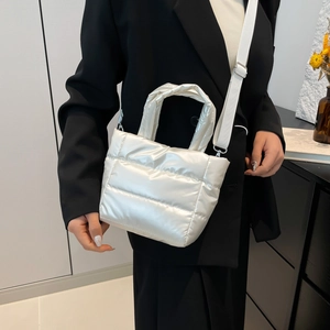 Sac seau matelassé blanc nacré pour femme avec bandoulière porté par un mannequin