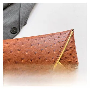 Detail of brown ostrich leather texture with gold metal corner on women's envelope clutch