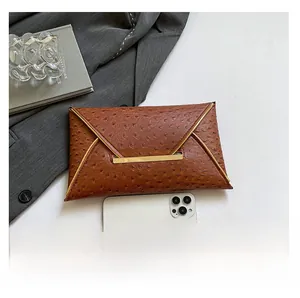 Macro shot of brown ostrich texture envelope clutch with V-cut gold metal trim and lock