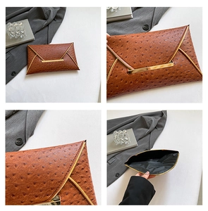 Macro view of brown ostrich-pattern embossed clutch featuring gold-tone hardware and lining