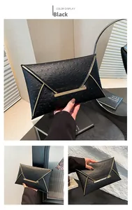 Detailed view of black envelope clutch featuring ostrich texture and gold metal trim