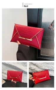 Macro detail of red ostrich-embossed leather clutch with elegant gold metal frame buckle