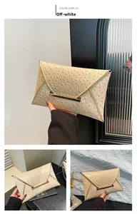 Detail view of off-white envelope evening clutch with ostrich pattern and gold metal trim