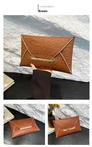 Detail of brown ostrich texture envelope clutch with gold metal trim and magnetic closure