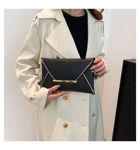 Detail of black ostrich embossed envelope clutch with elegant gold metal trim and texture