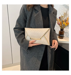 Detail of light beige ostrich texture envelope clutch with elegant gold metal trim