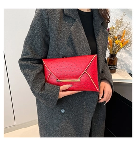 Detail of red ostrich embossed envelope clutch bag with gold metal trim and V-shaped flap