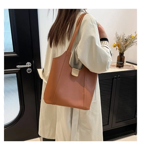 Detail of a brown leather shoulder bag with a magnetic buckle and large capacity