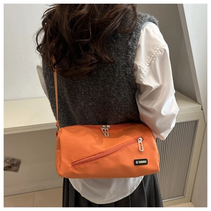Vue arrière du modèle portant un sac bandoulière en nylon orange vif avec étiquette