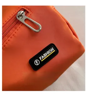 Gros plan sur la fermeture éclair argentée et le logo sur le sac en nylon orange