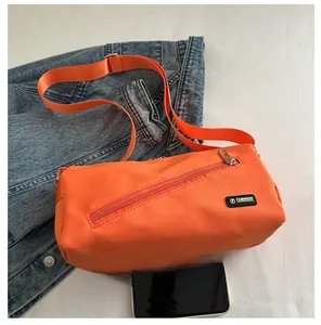 Détail du grand sac de voyage en nylon orange avec bandoulière et étiquette mode