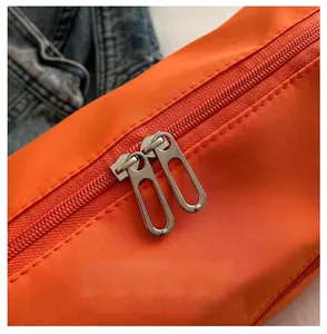 Vue macro détaillée des deux fermetures éclair métalliques sur un grand sac de voyage orange