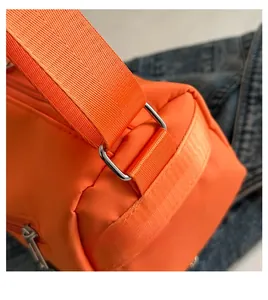 Détail de la boucle métallique et du tissu en nylon orange du sac de voyage