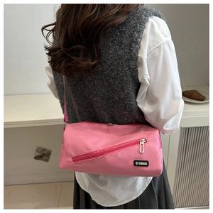 Vue détaillée du sac bandoulière rose cylindrique avec poche zippée et étiquette fashion