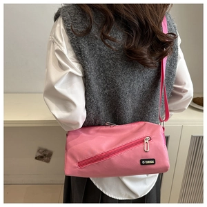 Détail du sac bandoulière en nylon rose avec étiquette mode porté par un mannequin