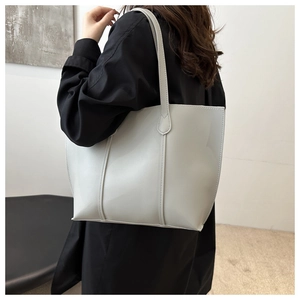 Close-up of light gray PU leather tote bag with vertical stitching and long shoulder handles