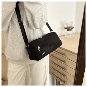 Détail du sac bandoulière noir minimaliste avec sangle réglable et poche zippée avant