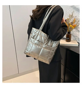 Champagne gold quilted down tote bag with metallic luster shown on a model's shoulder