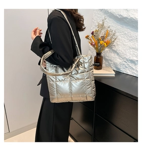 Detail of silver quilted tote bag with metallic finish shown on model in black suit