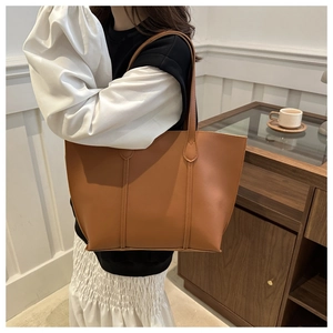 Détail d'un grand sac cabas en cuir marron caramel avec coutures verticales et ouverture large