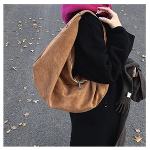 Detailed close-up of brown suede hobo bag with high-quality silver zipper and soft texture
